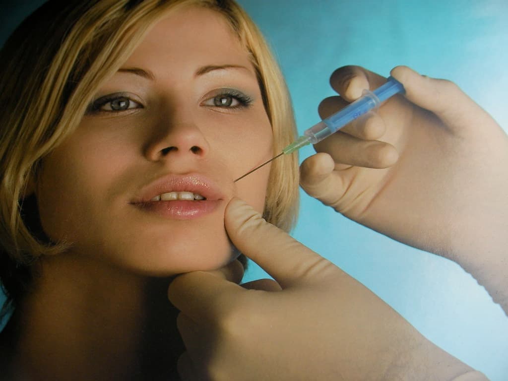 A woman gets an injection with botox in her cheek