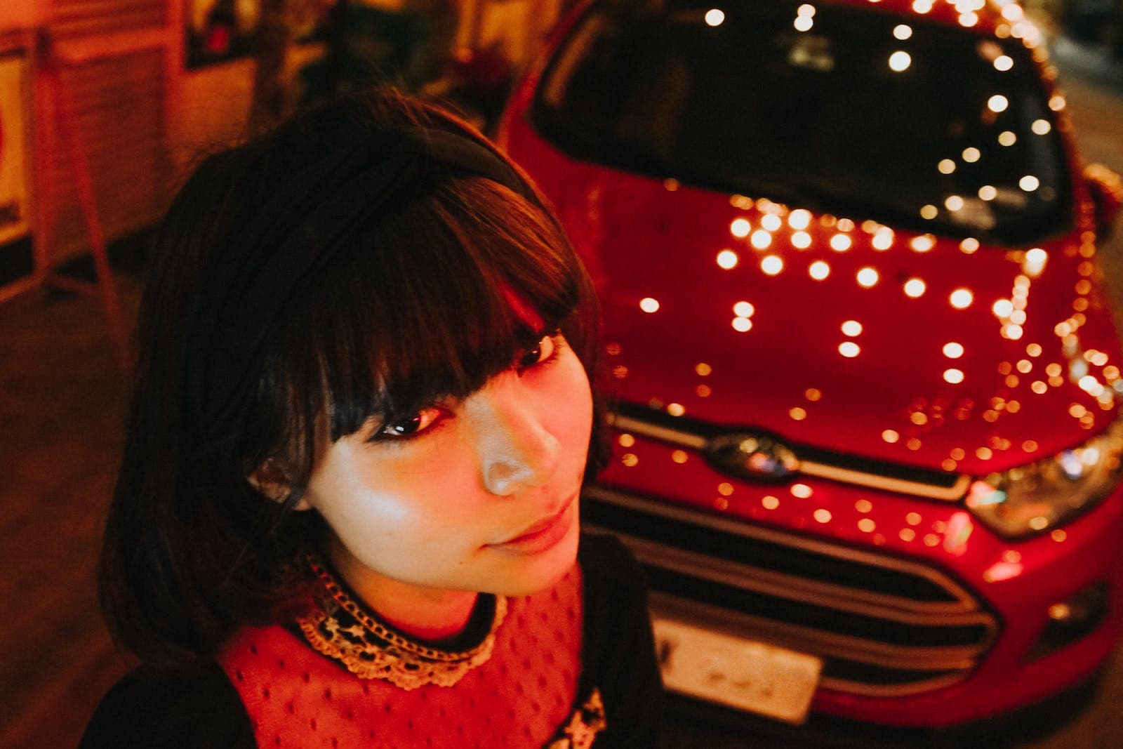 A woman in front of a red car