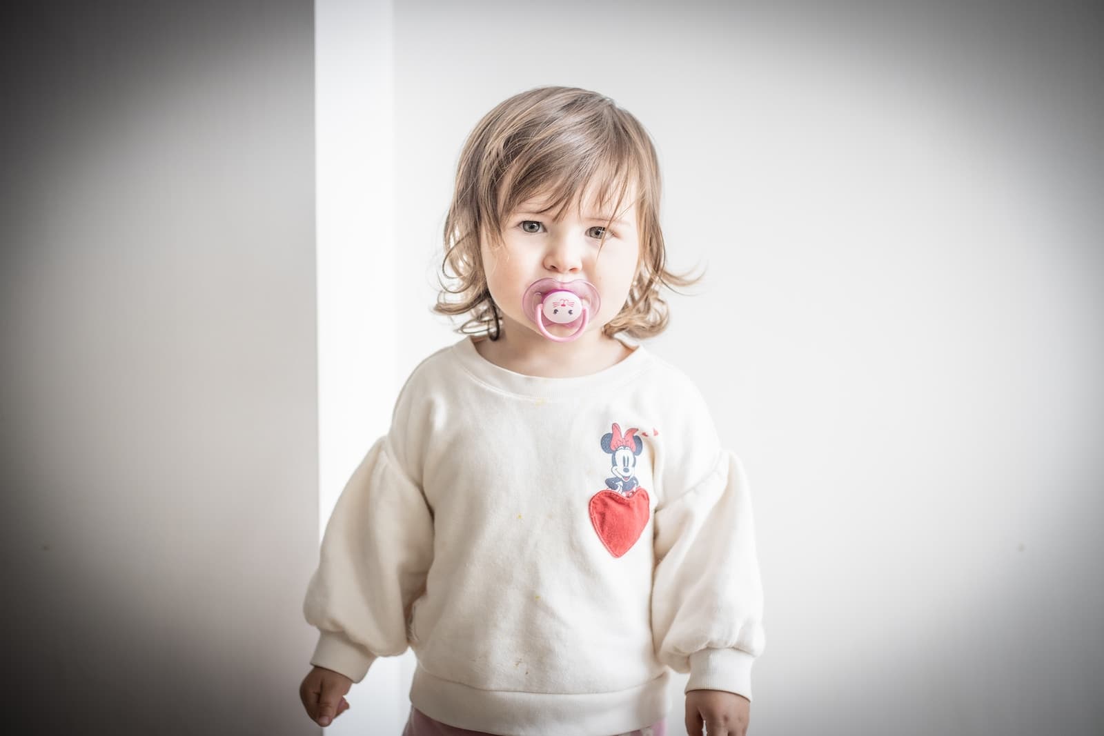 girl in white long sleeve shirt with a pacifier