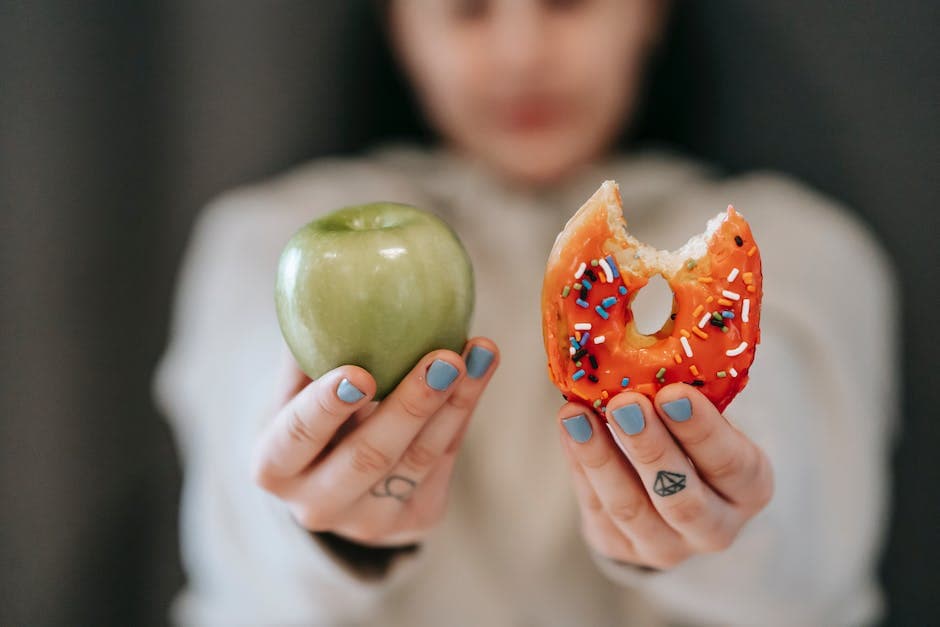 Woman showing apple and bitten doughnut