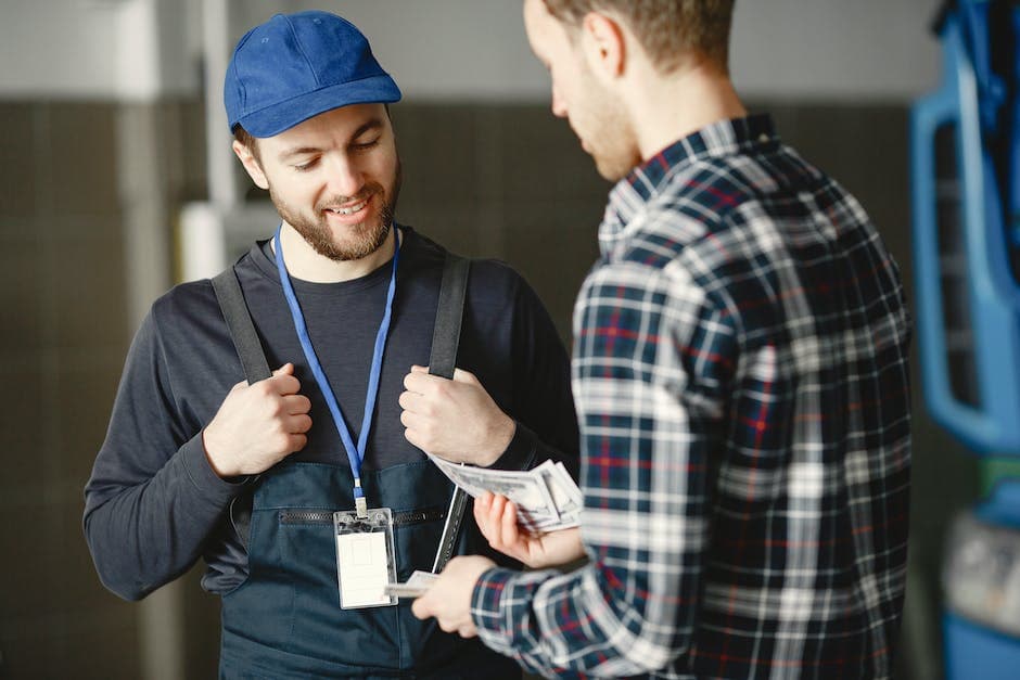Man in Plaid Shirt Giving Money to Bearded Man in Blue Cap and Overall