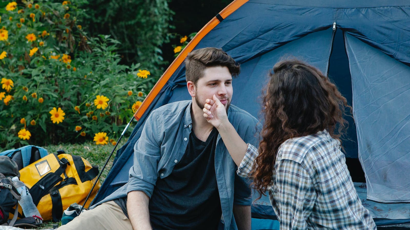 Young woman touching face of boyfriend during romantic camping picnic in own backyard