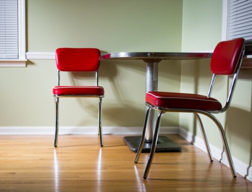picture of a room with green walls, a vinyl foor, a table and two red chairs