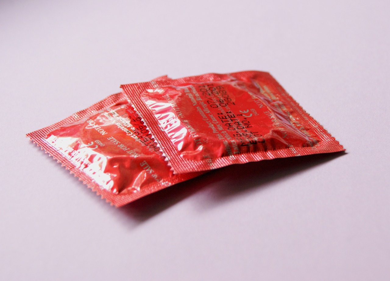 two red condom packages on a pink background