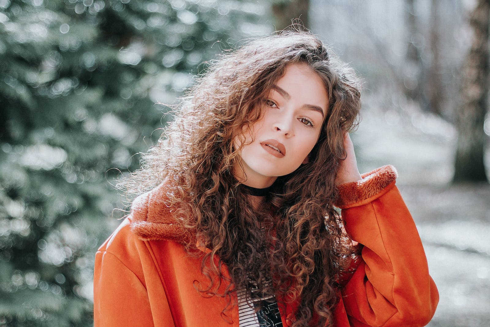Woman in Orange Zip-up Jacket with Curly Hair