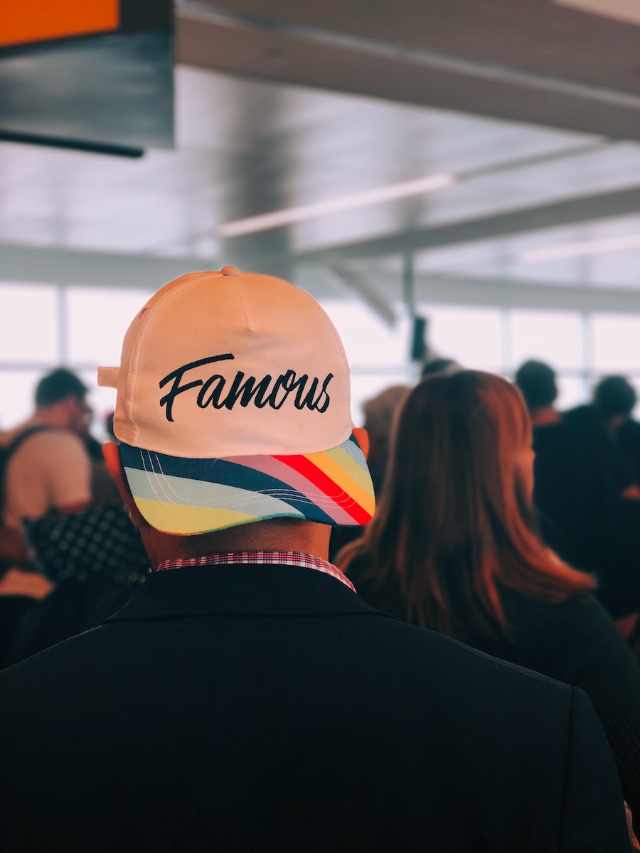man wearing multicolored Famous cap with the text famous