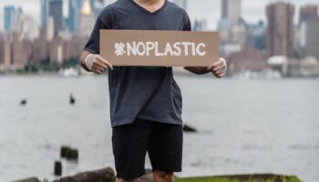 Man in Black Crew Neck T-shirt Holding the Beach Signage: No Plastic