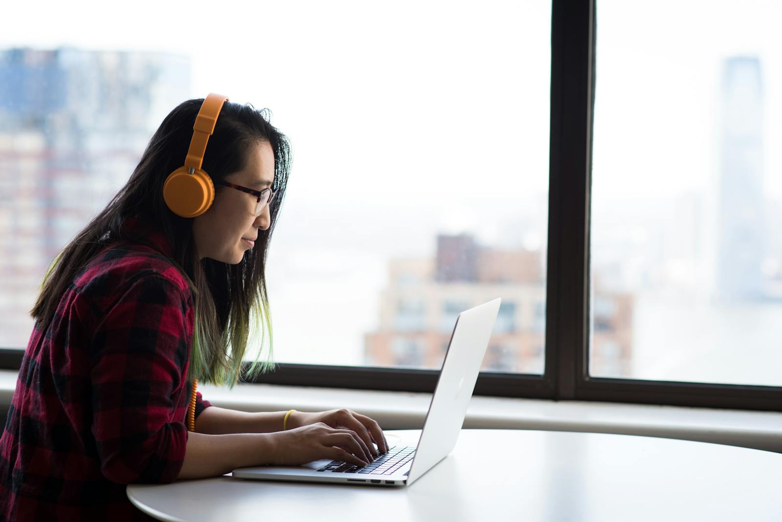 Photography of Woman Using Laptop and Wearing a Noise Cancelling Headphone