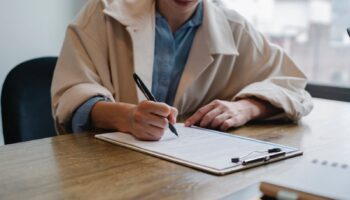 Focused woman writing in clipboard while hiring candidate