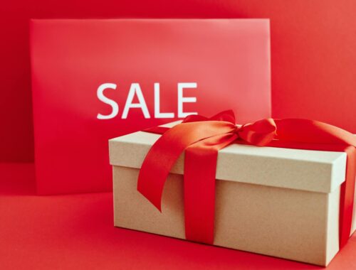 Cardboard Box with Red Ribbon Beside A Sale Sign