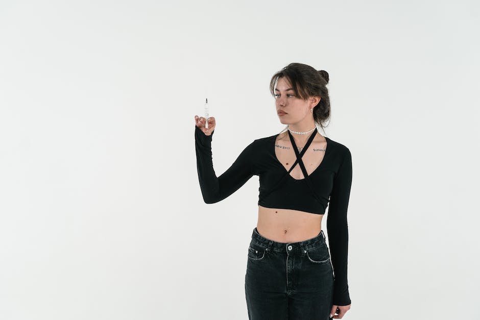 Woman in Black Crop Top and Black Denim Jeans Holding Clear Glass Bottle