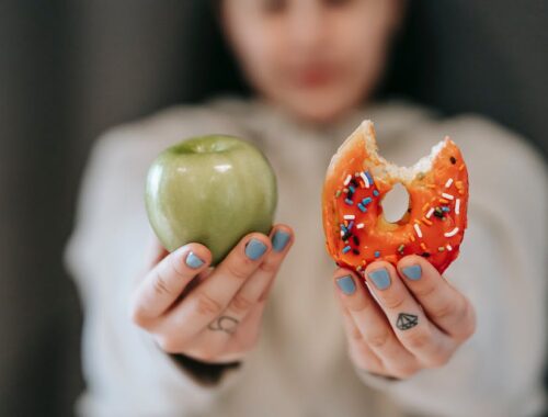 Woman showing apple and bitten doughnut