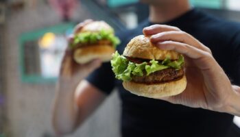 Person Holding Two Hamburgers