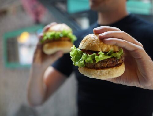 Person Holding Two Hamburgers