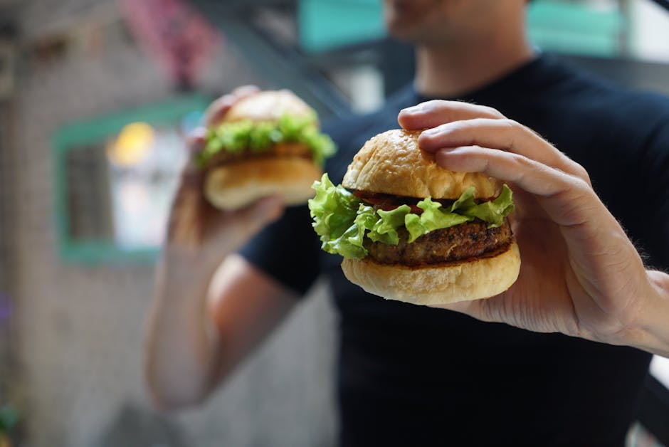 Person Holding Two Hamburgers